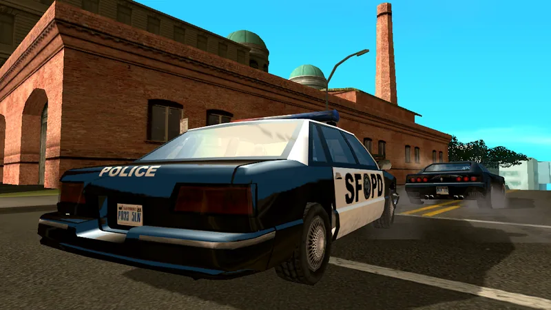 Captura de GTA: San Andreas com um carro-patrulha azul e branco marcado POLICE e SFPD, visto de trás junto a um edifício de tijolo com chaminé alta, e outro carro escuro a arrancar mais à frente